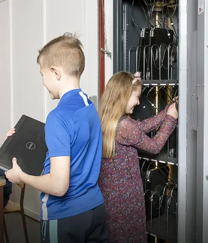 elever foran et it-skab med computere på en folkeskole