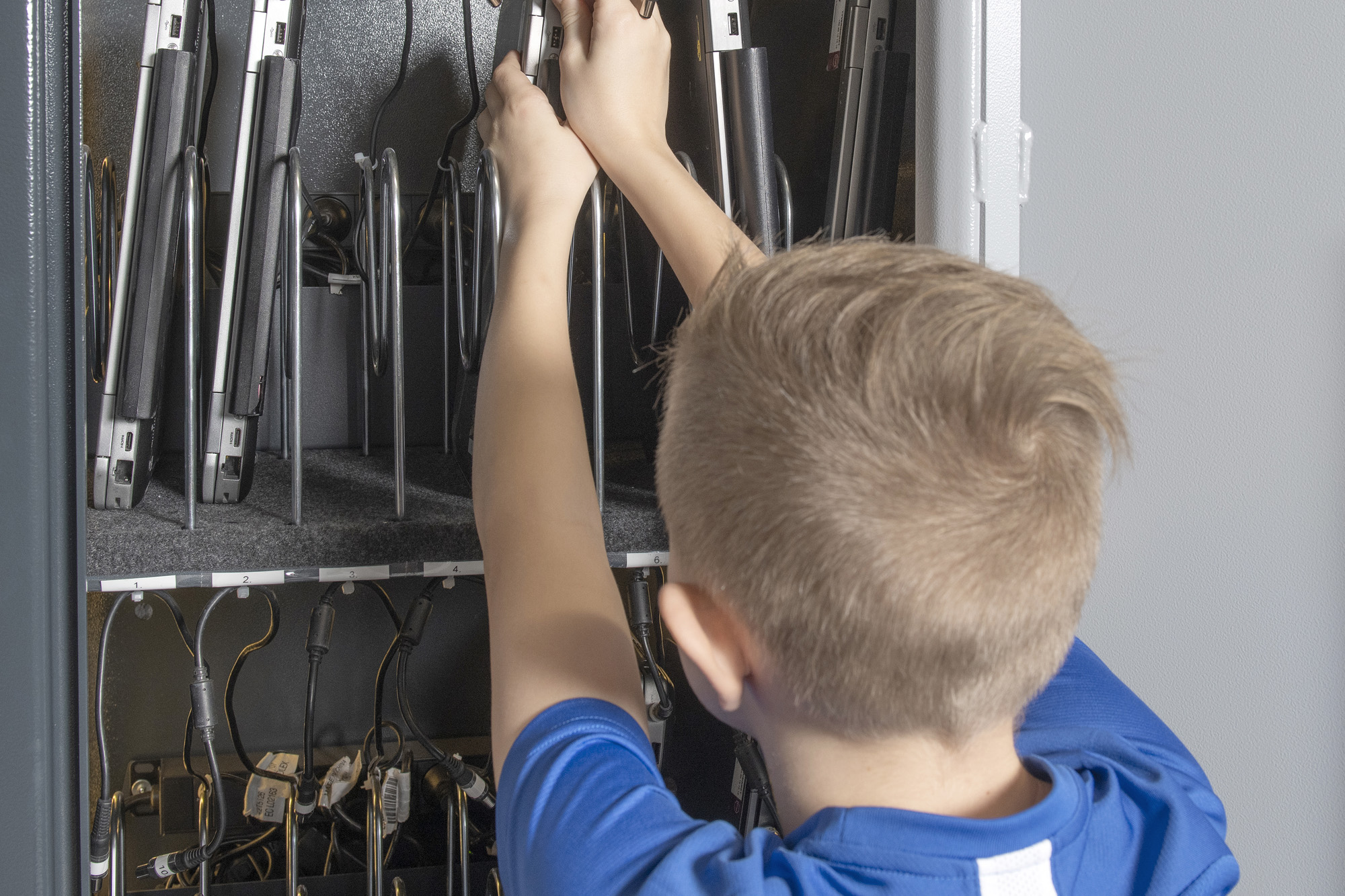 dreng på en skole, der tager en pc ud af et computerskab